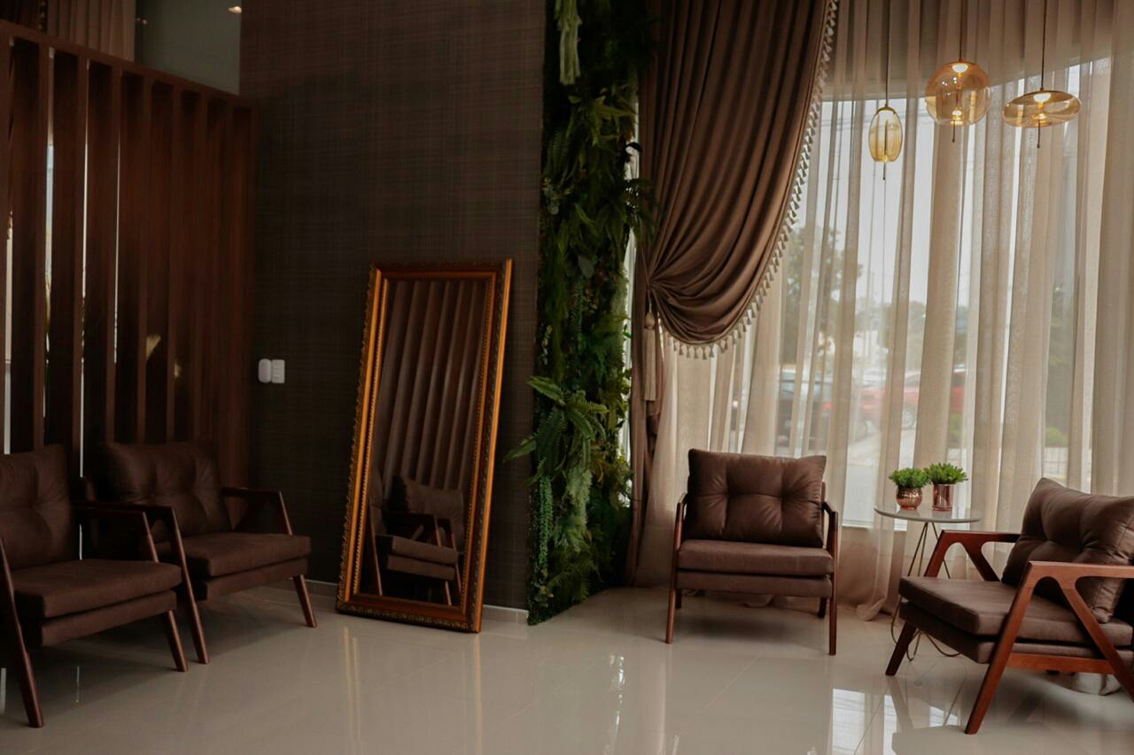 Sala de espera do Centro de Beleza Luz do Sol, com poltronas de couro, espelho dourado e parede de plantas